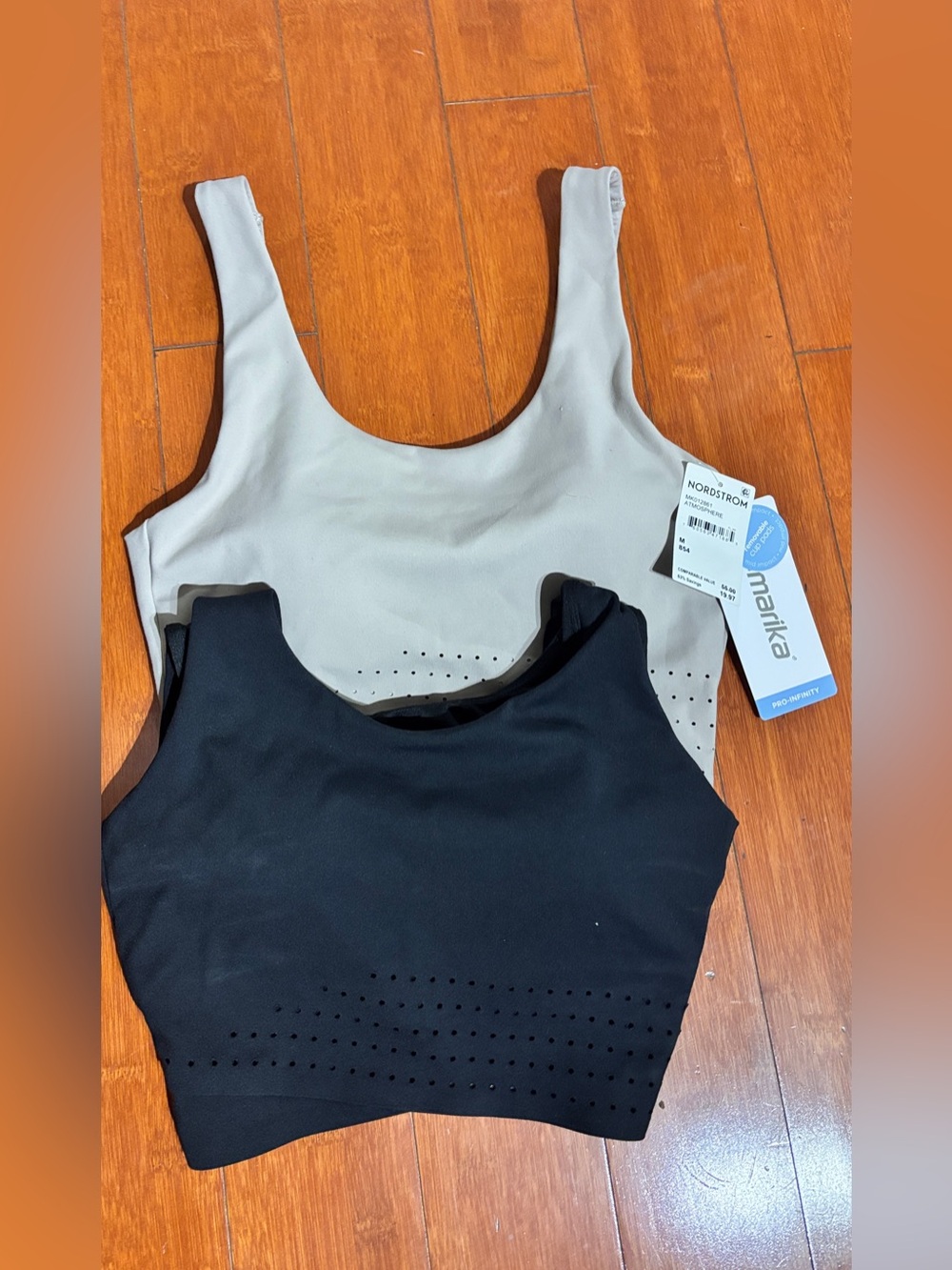 2 Marika M black and tan sports bras with perforated panel on the lower front